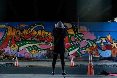 穿着蓝色外套的女人站在墙前涂鸦